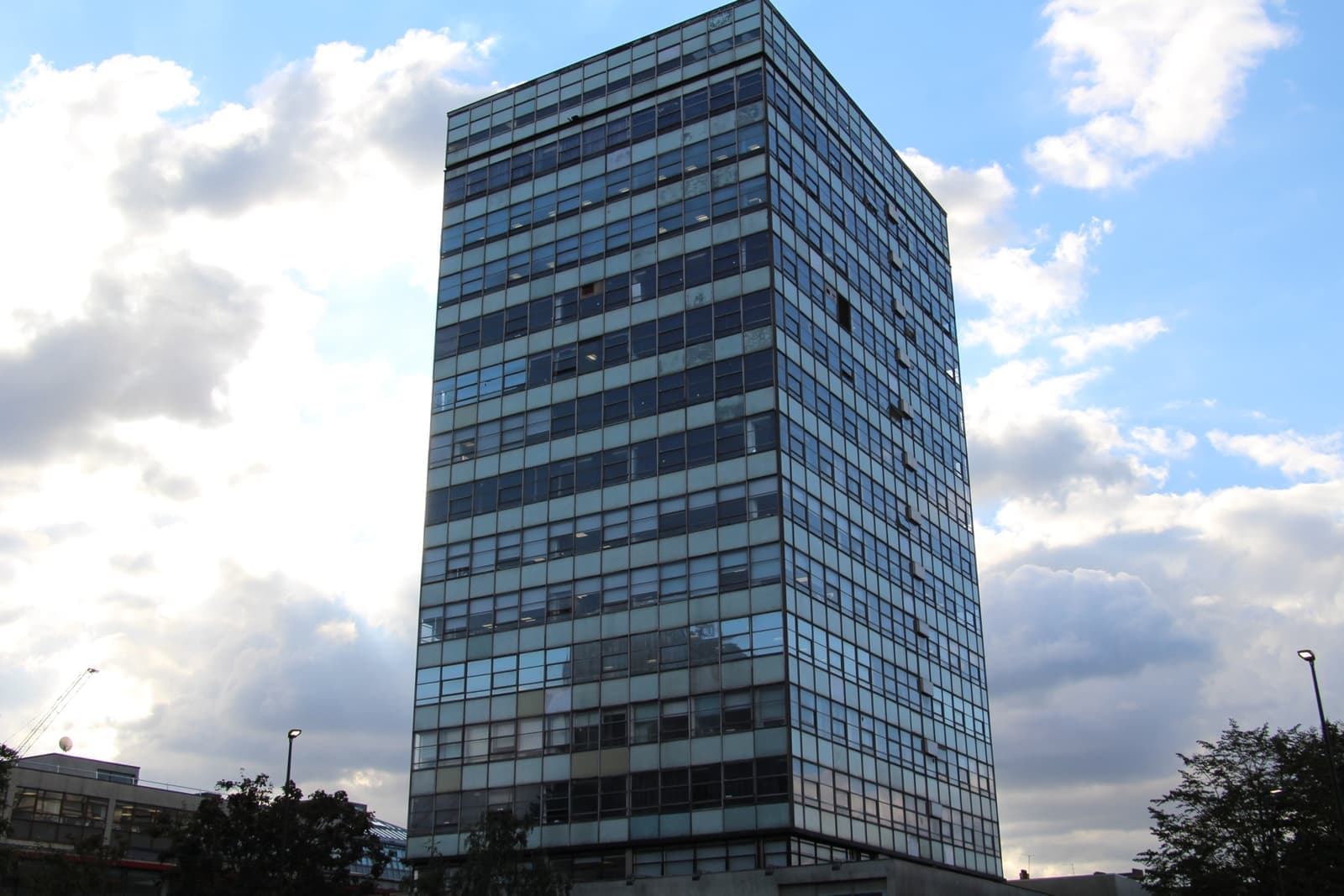 A glass and concrete tower block against a blue sky with clouds