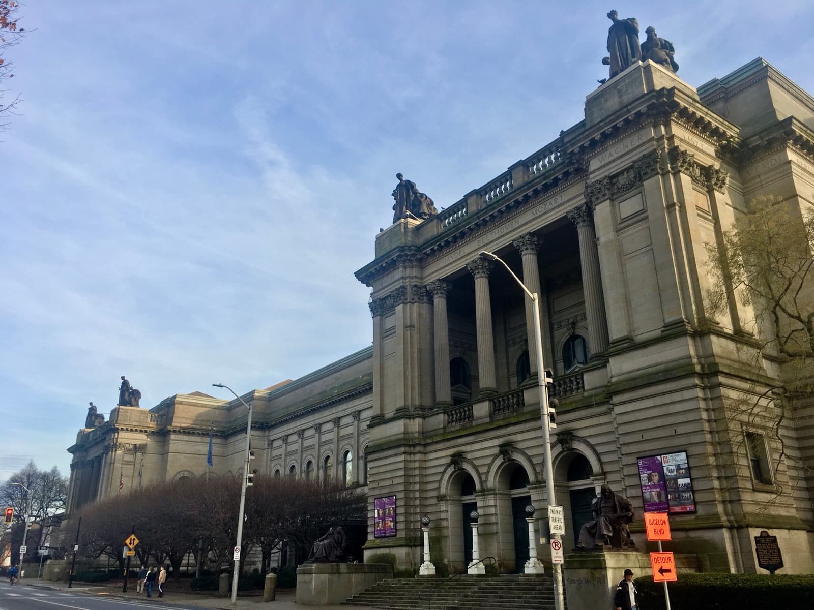 A long ornate stone museum front with statues on the roofline