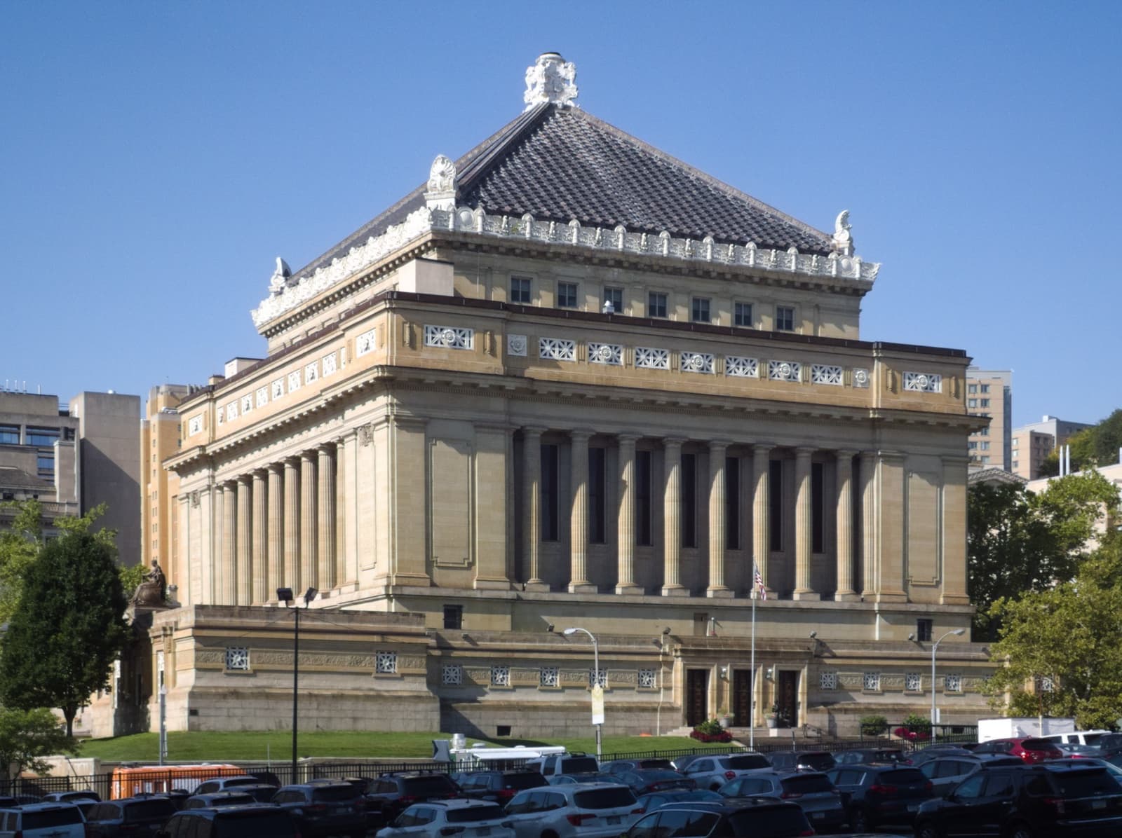 A colonnaded stone memorial hall with a stepped roof under a blue sky