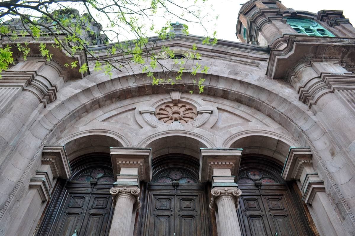 Carved stone arches over three dark wooden church doors
