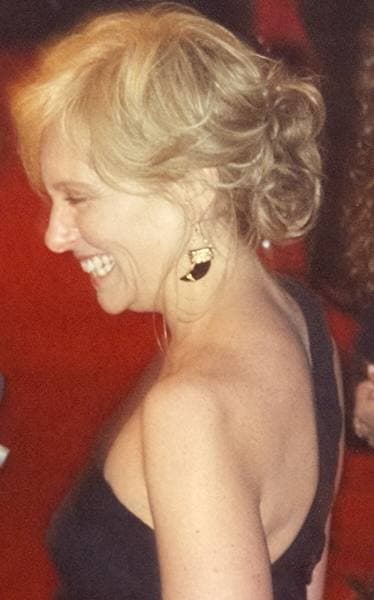Toni Collette in profile, laughing, her fair hair pinned up