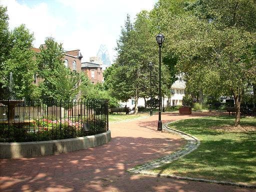 Brick paths, lamp posts and railings in a small leafy square