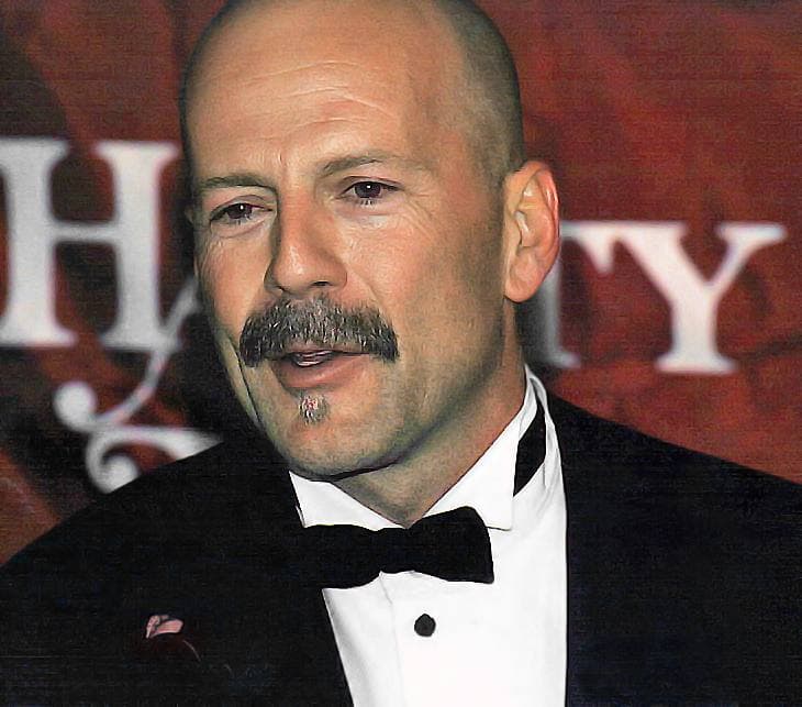 Bruce Willis in a black bow tie, speaking, with a moustache and goatee