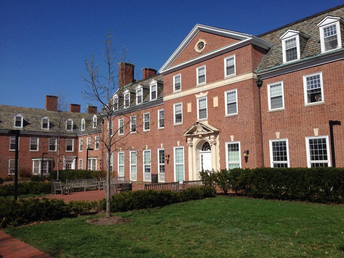 A long three-storey brick residence hall with dormer windows behind a lawn