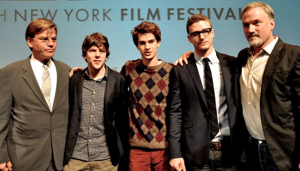 Five men standing arm in arm on a stage in front of a New York Film Festival backdrop
