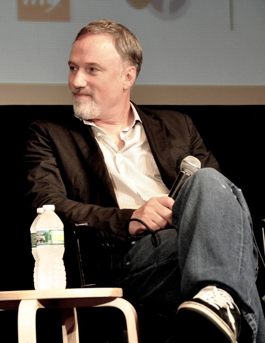 David Fincher with a grey beard, speaking into a microphone