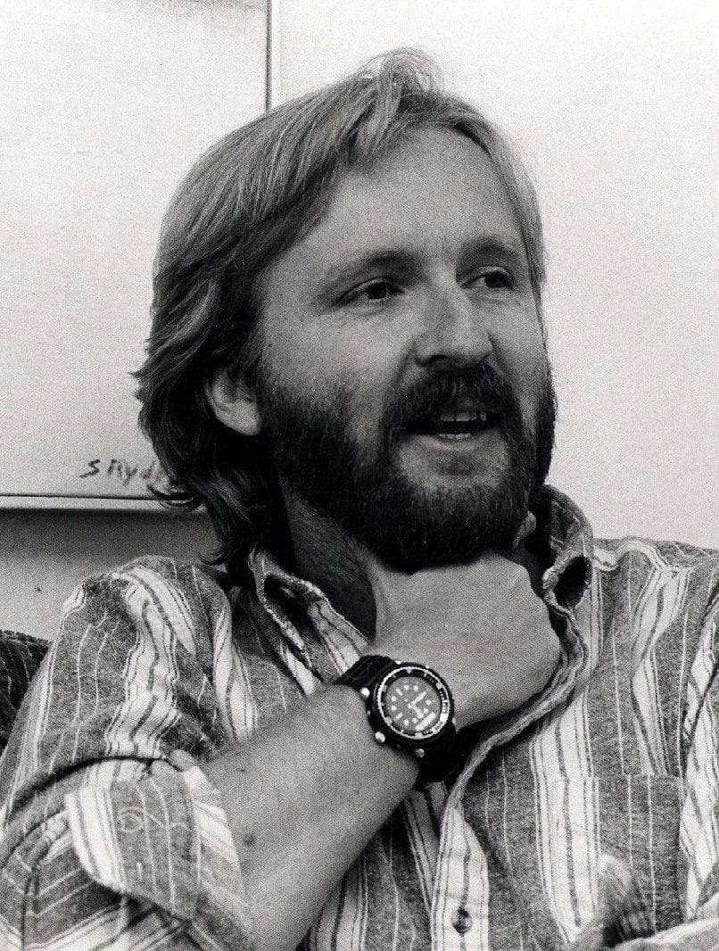 James Cameron in 1986, bearded, in a striped shirt, hand at his chin