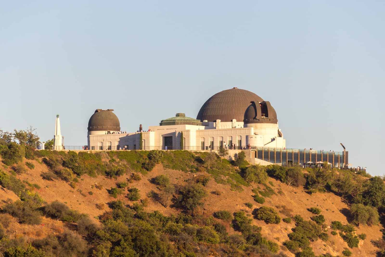 The white observatory with its three domes on a scrubby hillside at dusk