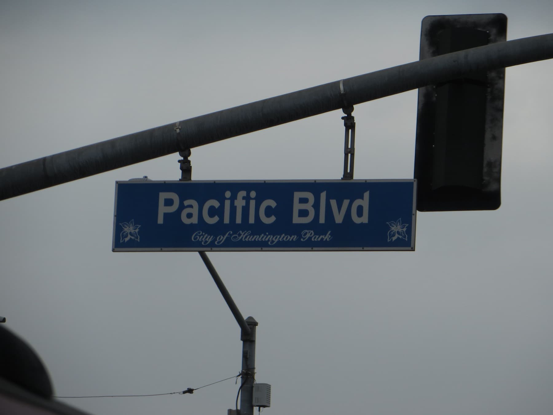 A blue Pacific Blvd street sign against a grey sky