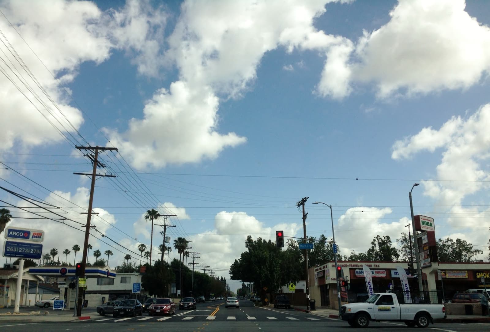A wide valley boulevard with palm trees and power lines