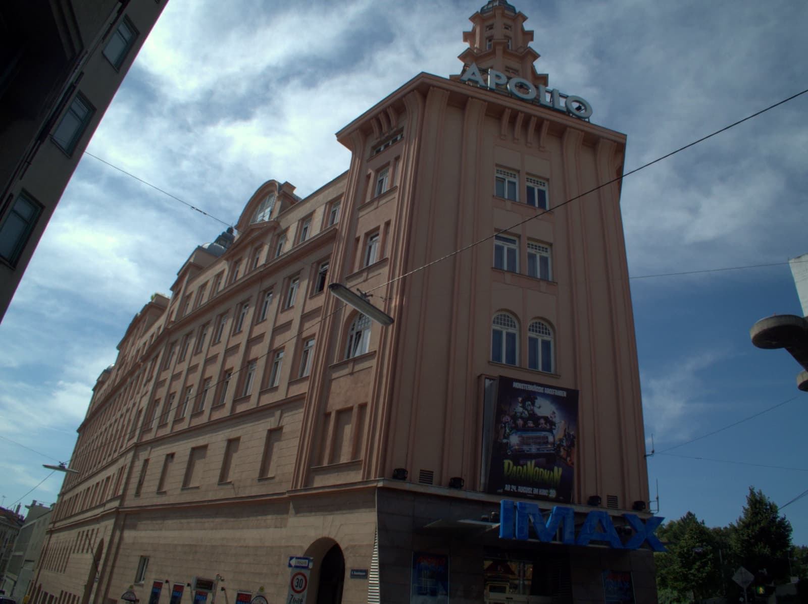 A tall pink cinema tower on a street corner