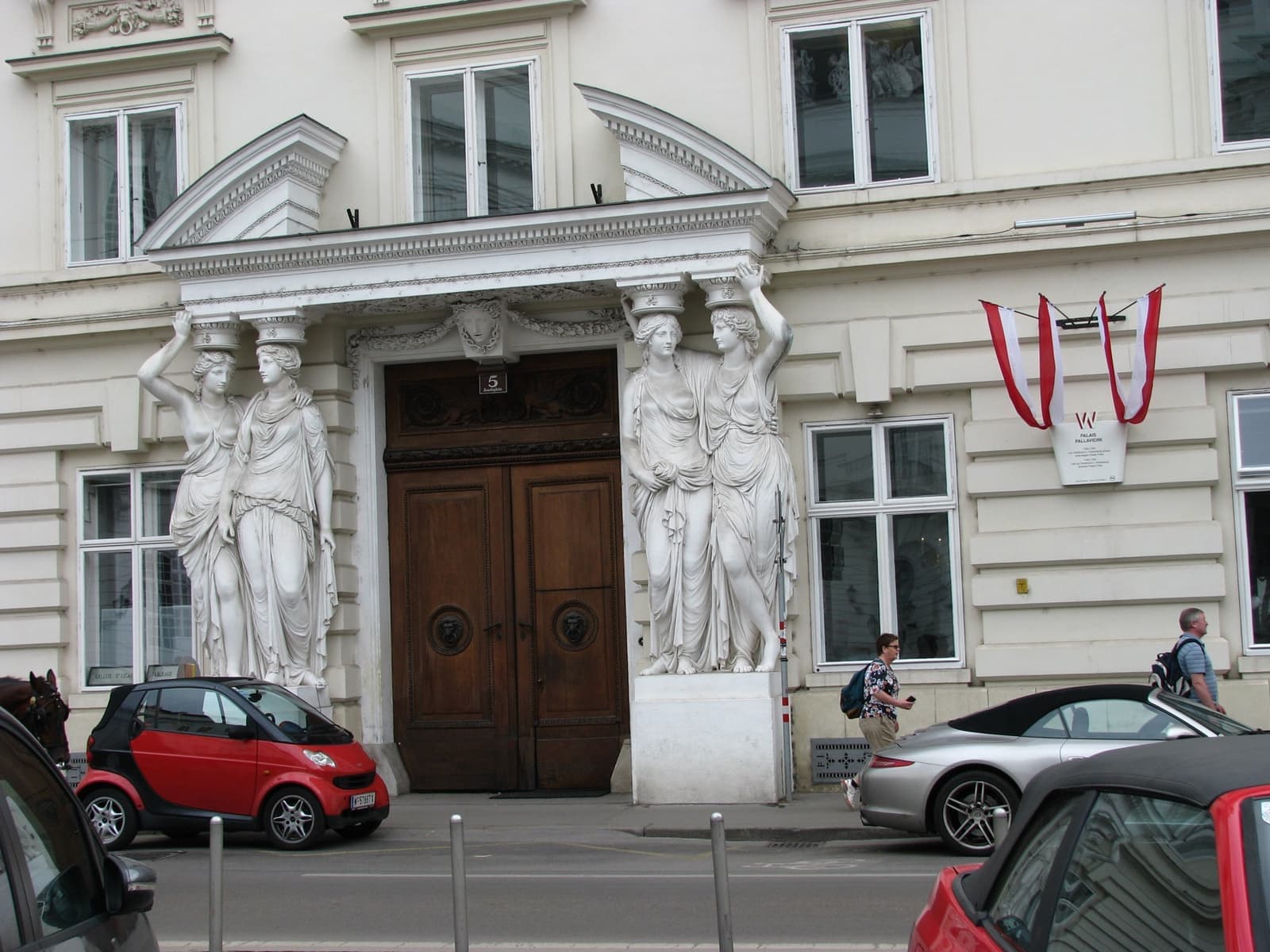 Four stone caryatids flank a tall wooden double door