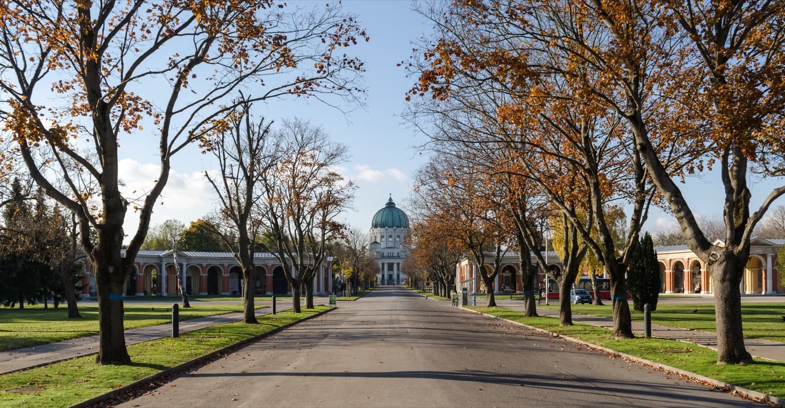 A long straight avenue of autumn trees leading to a domed church