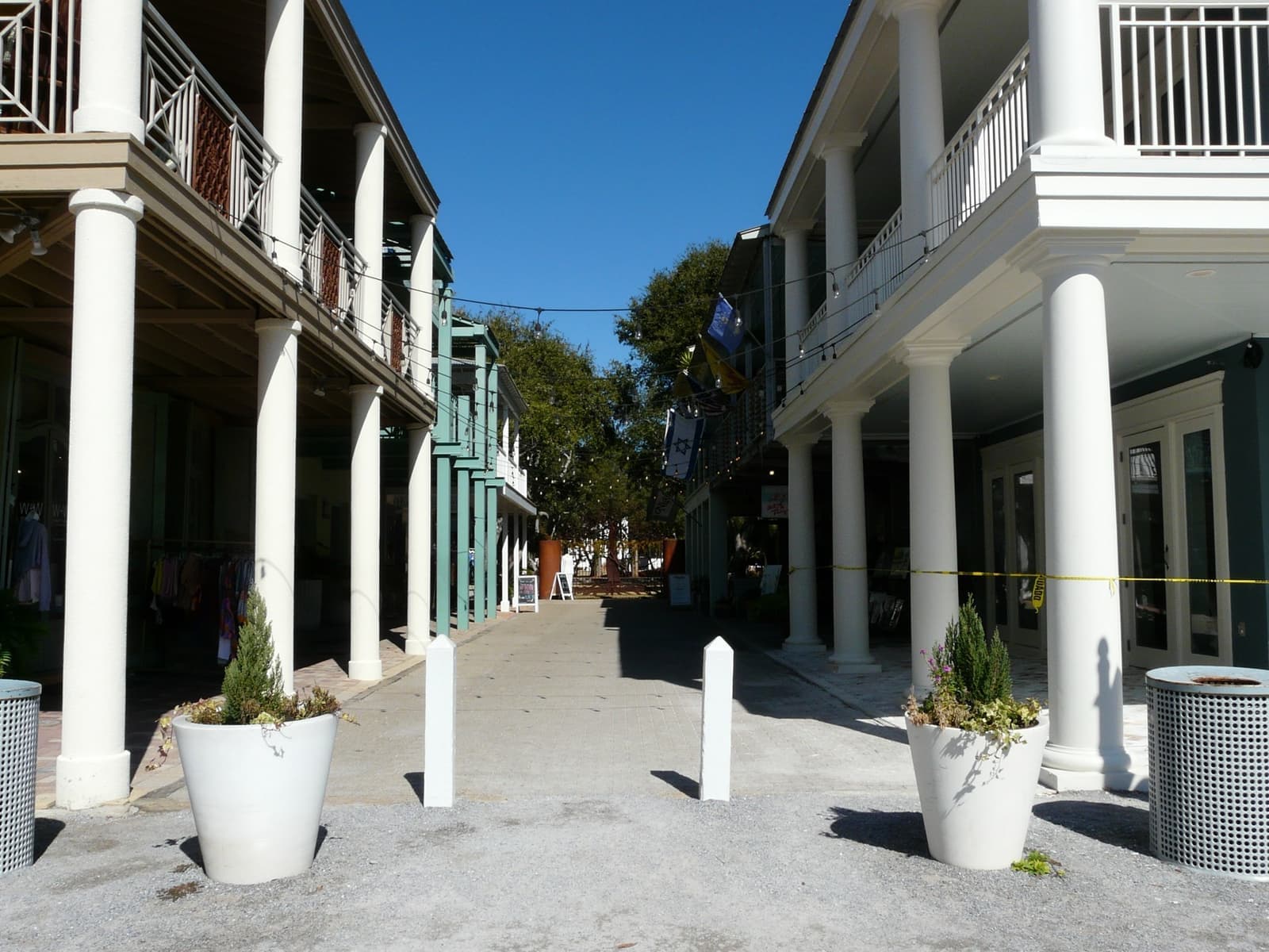 A narrow pedestrian lane between two white two-storey arcades with columns and planters