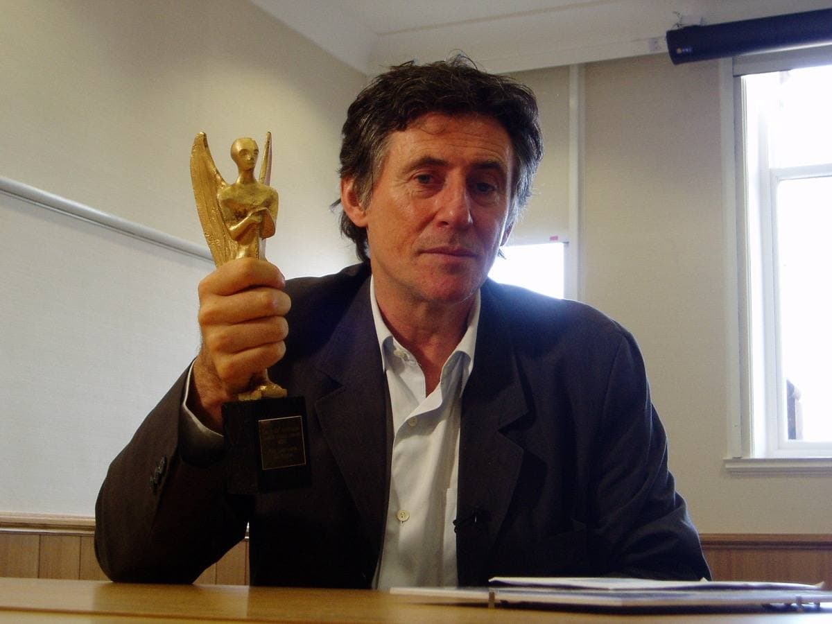 Gabriel Byrne holding a small award