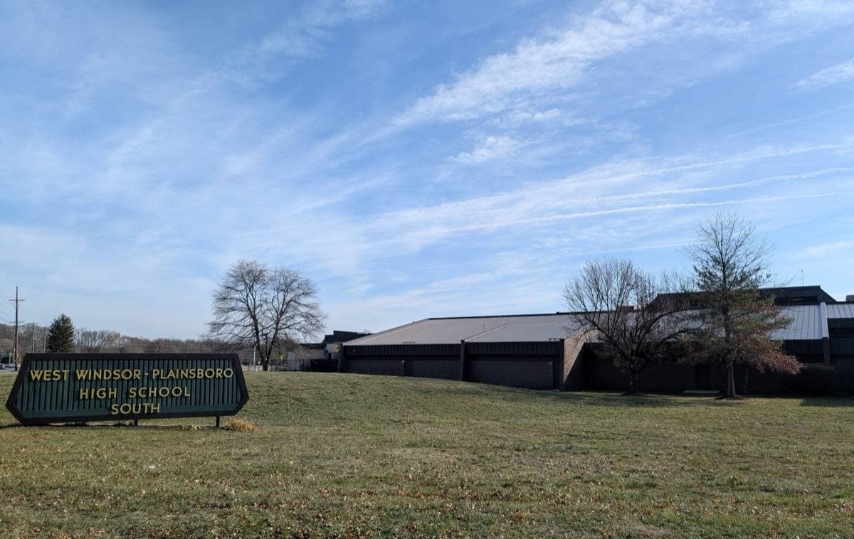 A low brick school building behind a lawn