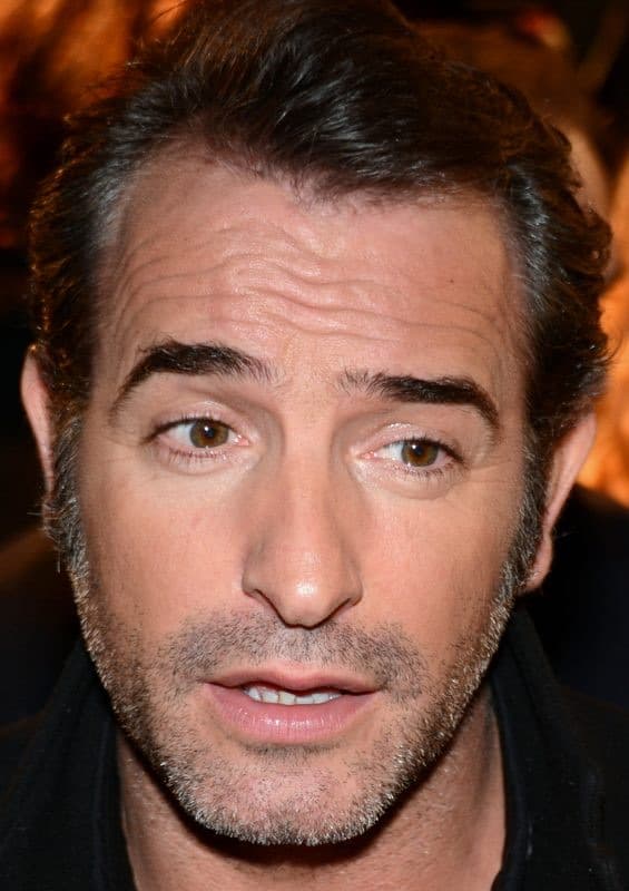 Jean Dujardin in a dark suit, smiling