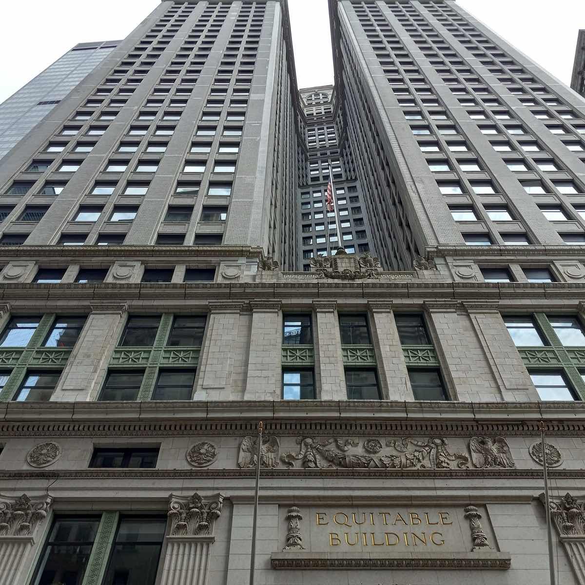 The pale stone mass of the Equitable Building rising over Broadway