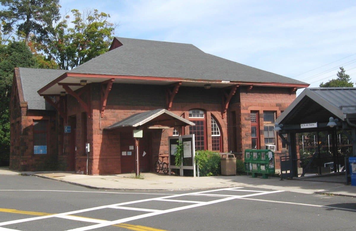 A small stone railway station building under trees