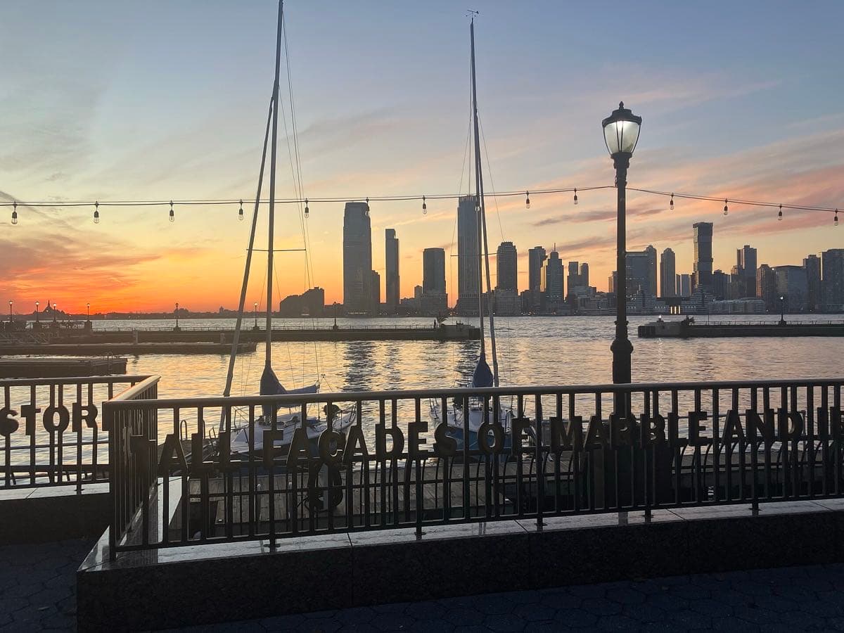 Yachts moored in a harbour in front of glass towers at sunset