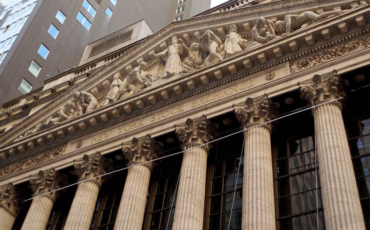 The columned front of the New York Stock Exchange with a huge American flag