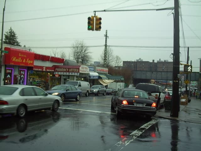 A Queens street with shops and apartment blocks