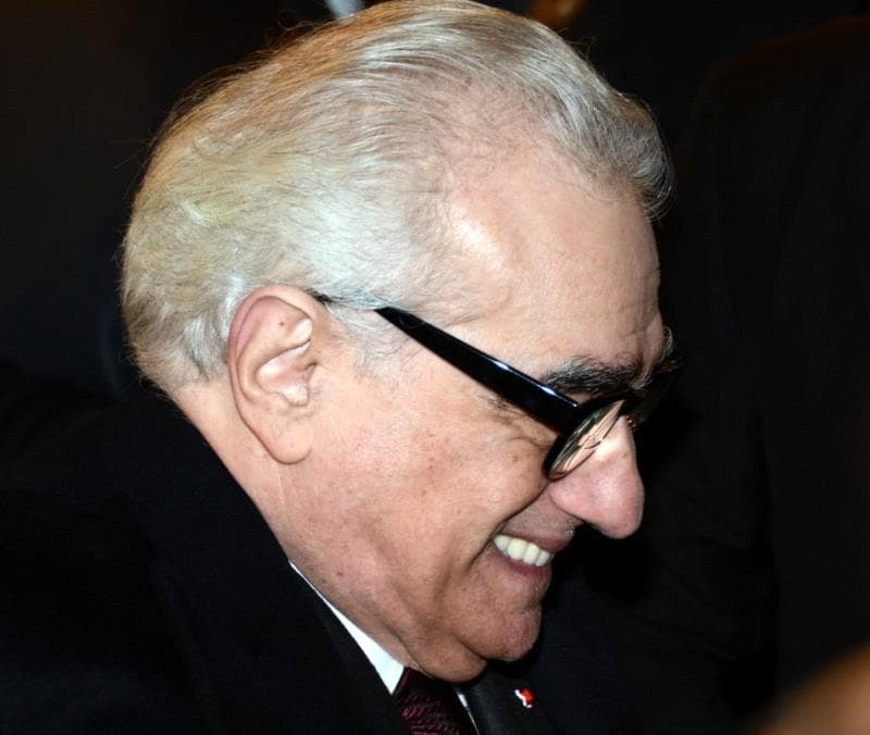 Martin Scorsese in glasses and a dark suit, smiling