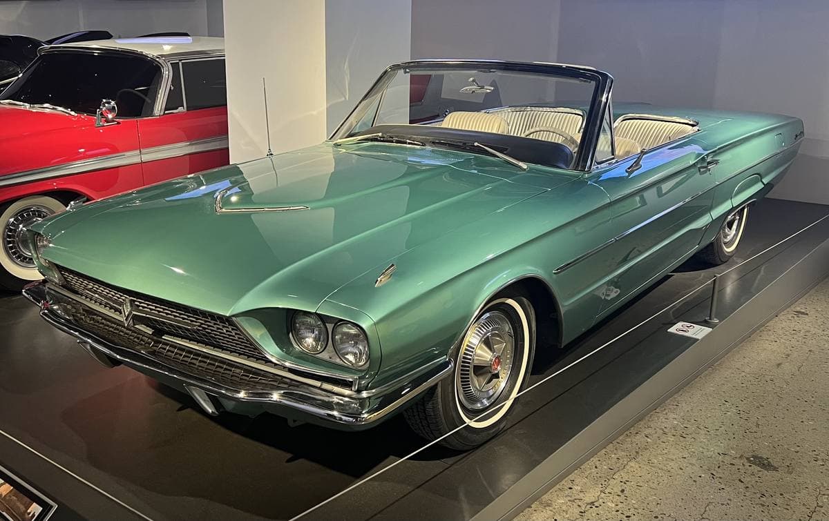 A sea-green 1966 Ford Thunderbird convertible, roof down, on a museum plinth