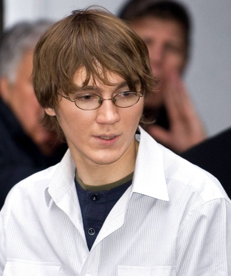Paul Dano in glasses and a white shirt, looking down, in a crowd