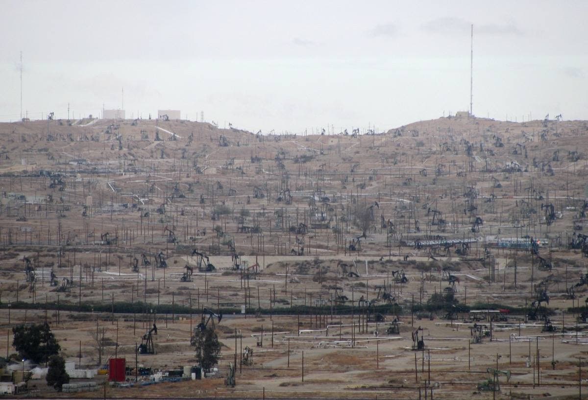 Low hills dense with pump jacks and pipework, seen from a bluff
