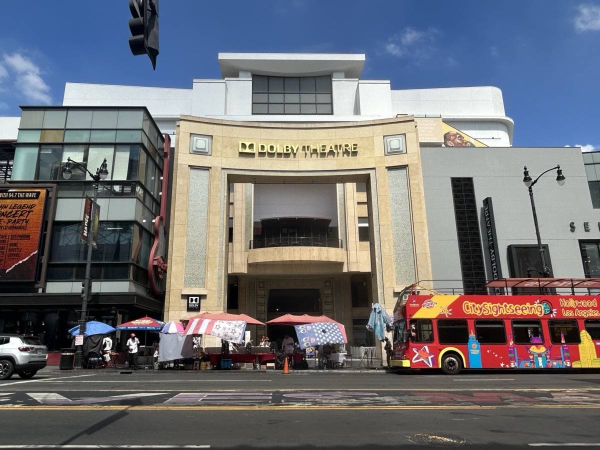 The pale columned entrance of the Dolby Theatre on Hollywood Boulevard with a tour bus