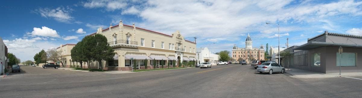 A wide street panorama of a small Texas town with a cream hotel and a domed courthouse