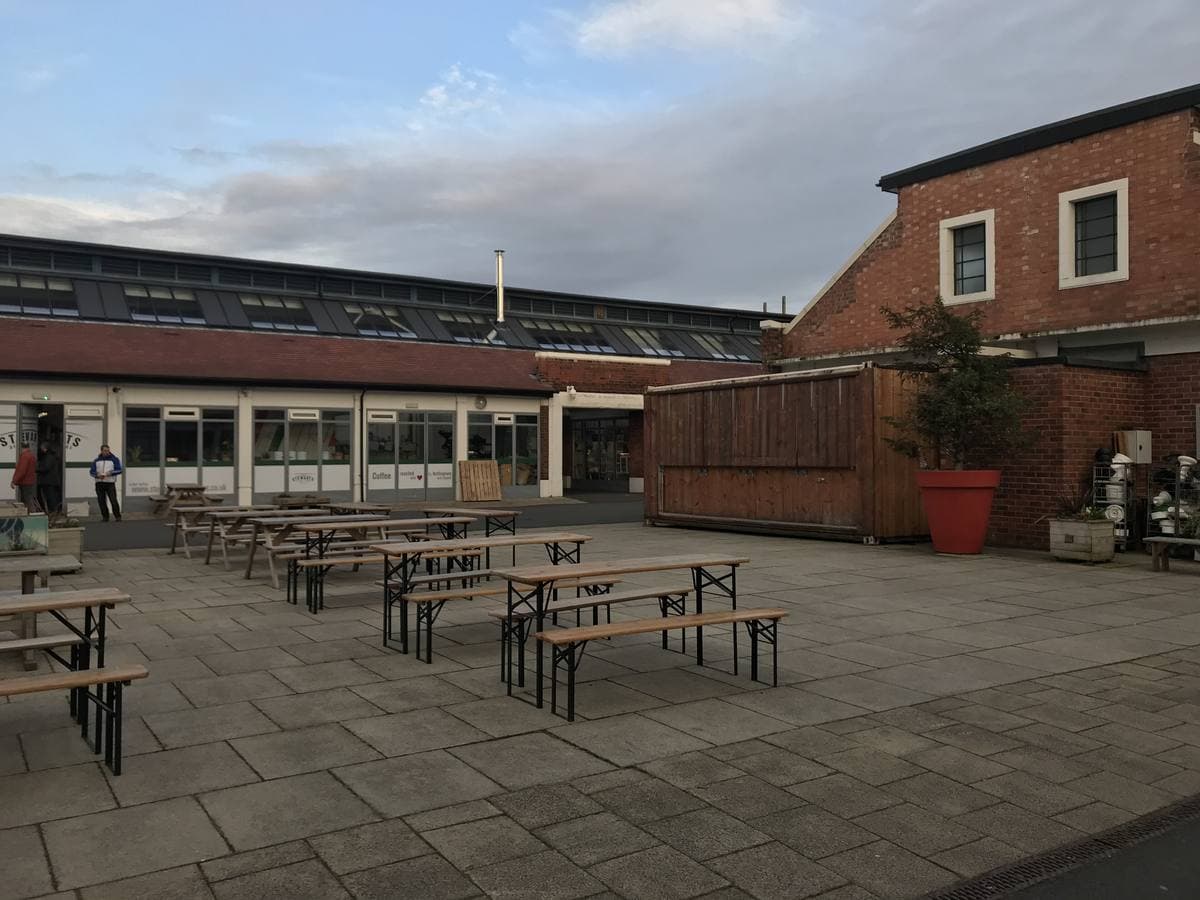 Benches in the courtyard of Sneinton Market, low brick market buildings around