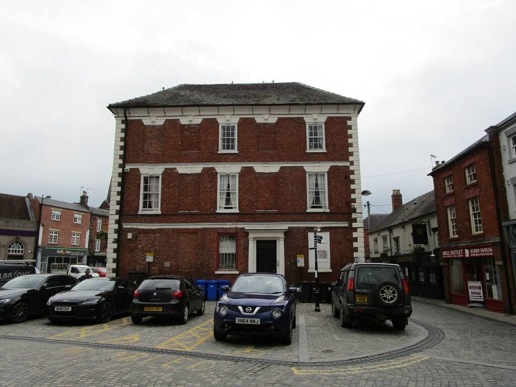 A brick Georgian building on Uttoxeter's market place with parked cars