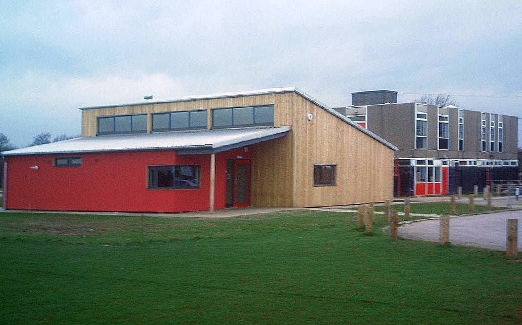 A red-and-timber school building on a lawn