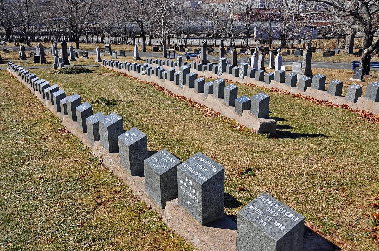 Rows of small grey granite headstones on a grass slope