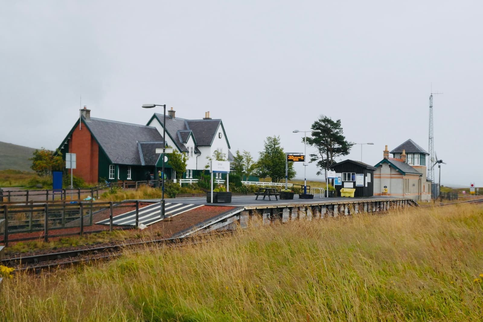 Two platforms on open moorland, a dark station house and a small signal box beyond the rails