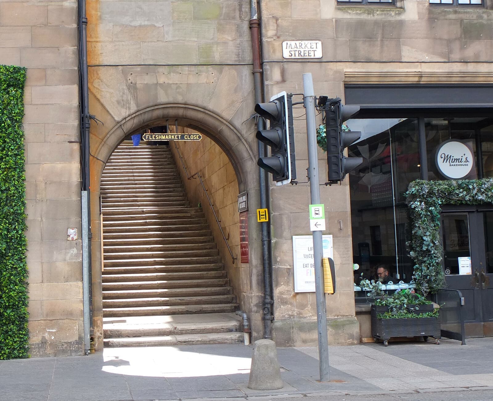 Stone steps rising through an arched close off a cobbled street