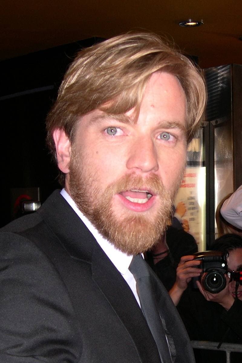 Ewan McGregor, sandy-haired and bearded, in a dark suit, mid-sentence