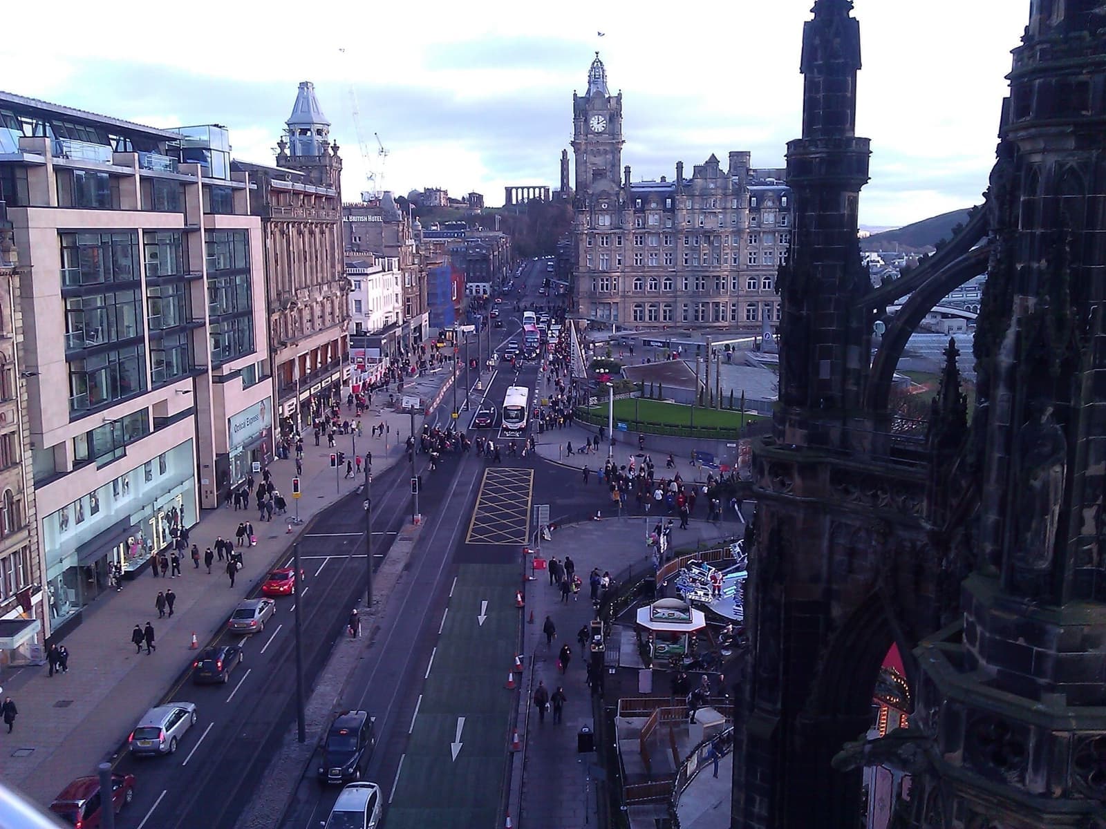 Looking down on a busy Princes Street with shops on the left and a clock tower at the far end