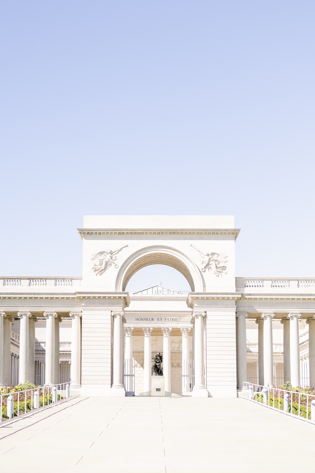 A classical archway and colonnade seen down a path