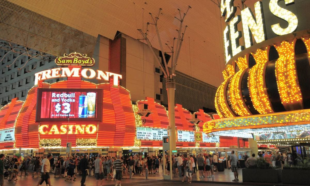 A pedestrian street packed with people under bright red and gold casino signs