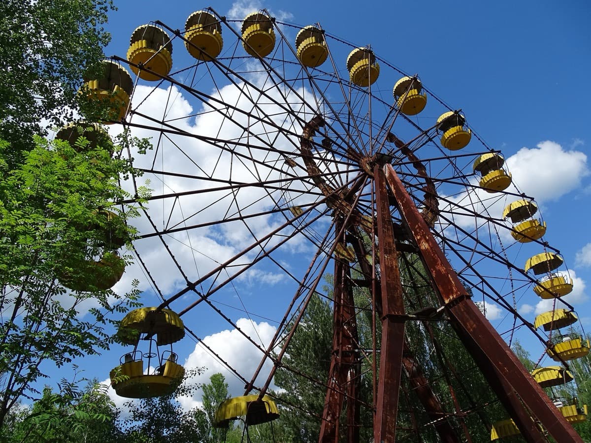 A rusted Ferris wheel among weeds and trees
