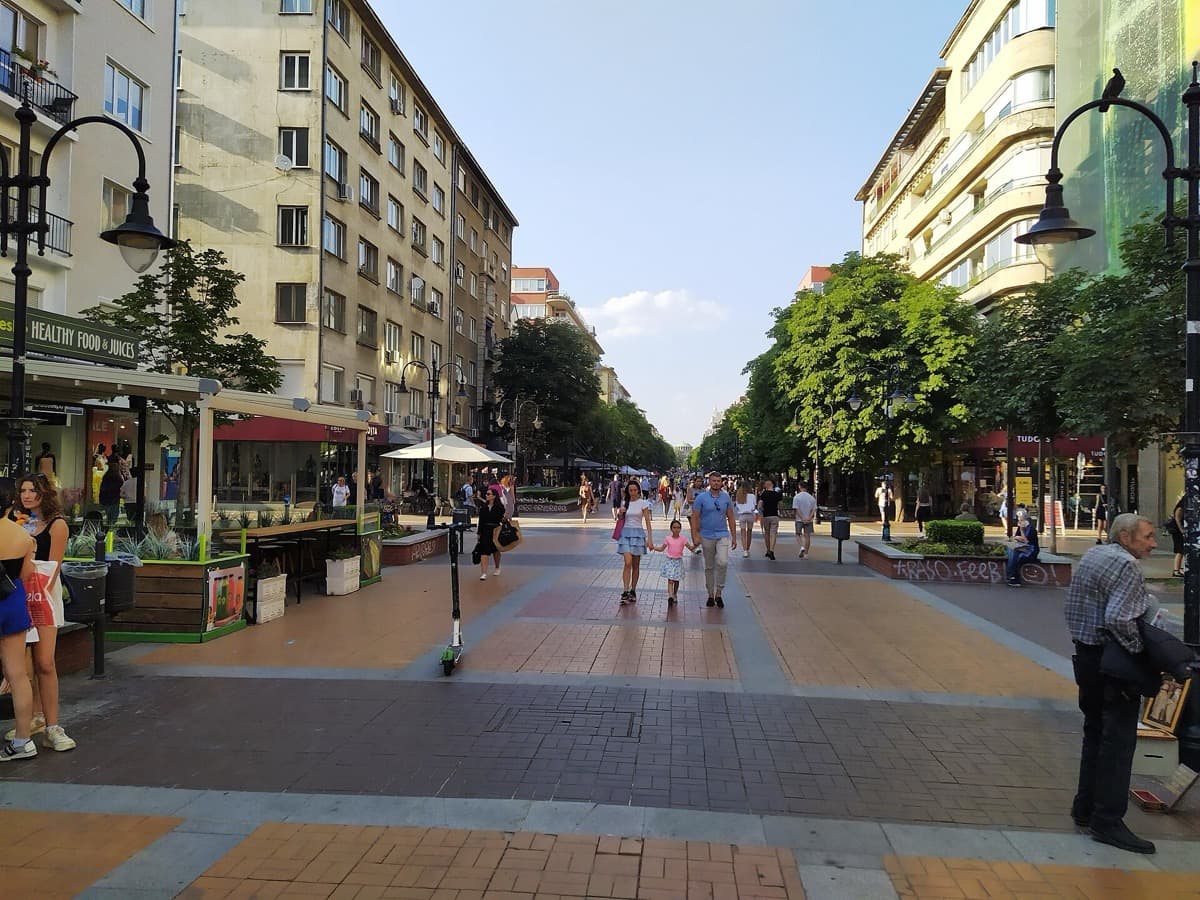 A pedestrian boulevard with trees and mountain behind