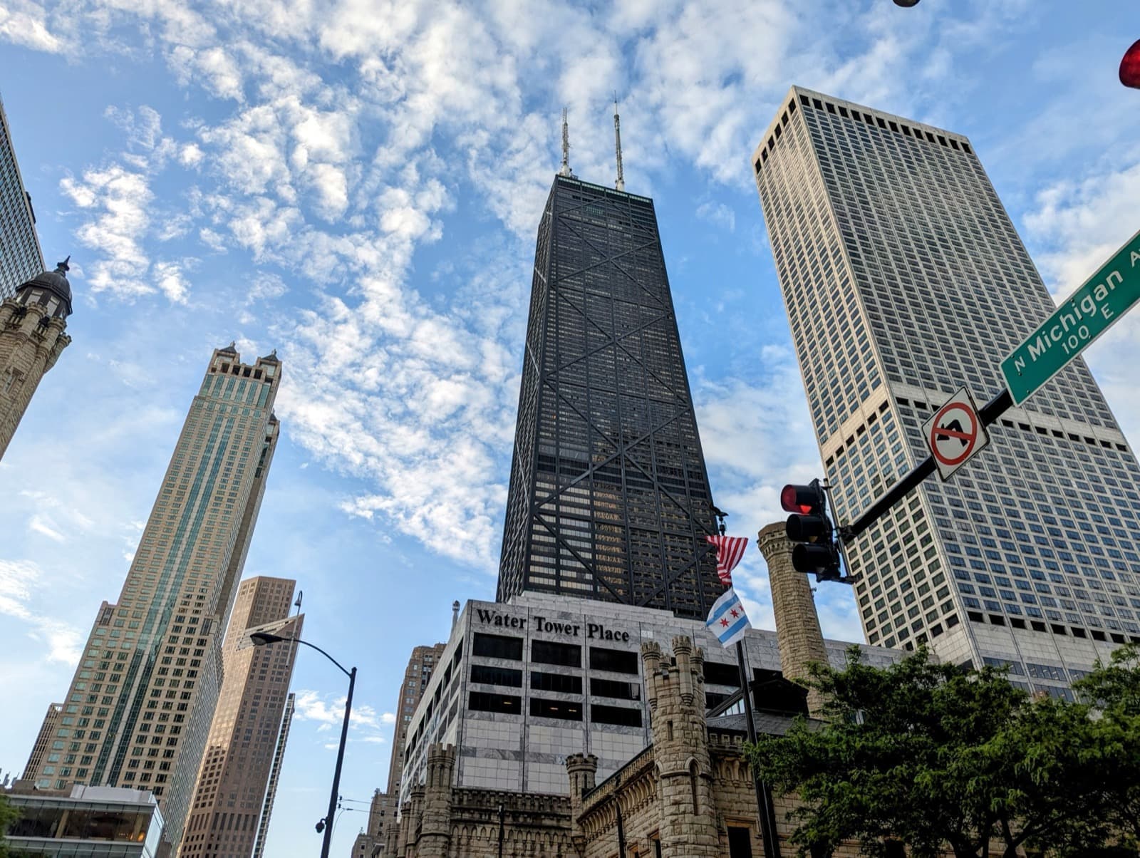 A black tapering skyscraper with cross-braces seen from the street