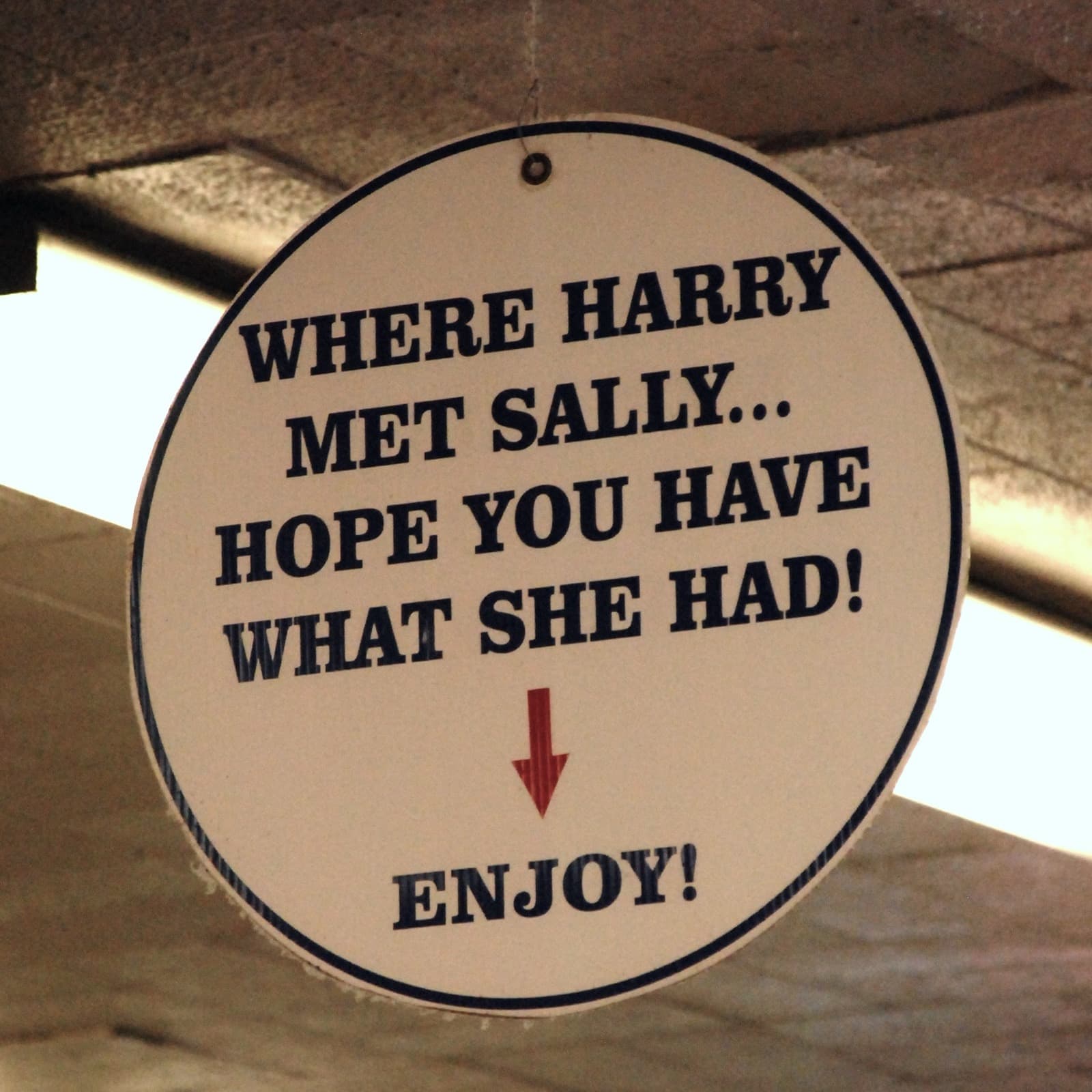 A round hanging sign reading Where Harry met Sally... hope you have what she had! with an arrow pointing down