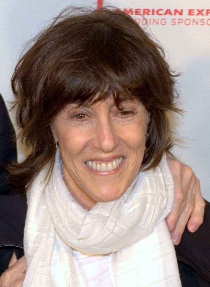 Nora Ephron laughing, in a pale scarf, with dark hair and a fringe
