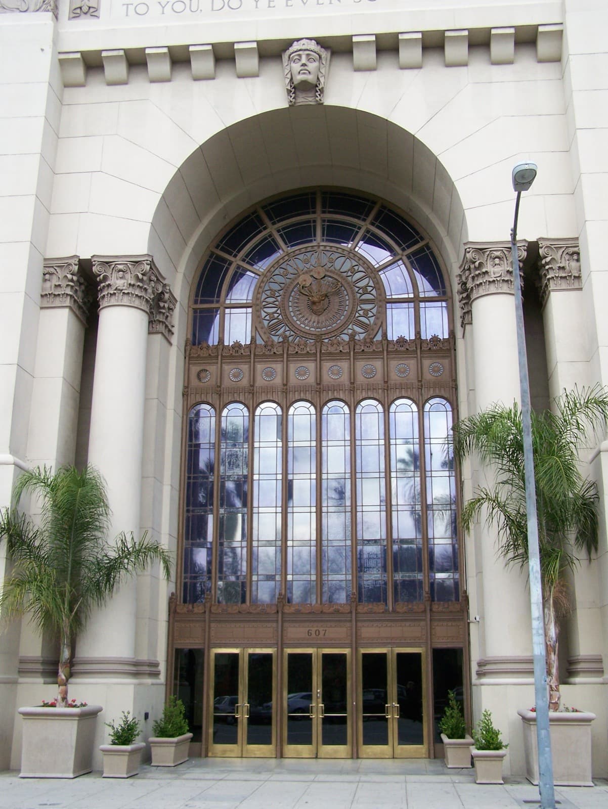 A tall arched entrance with columns and a large leaded window above glass doors