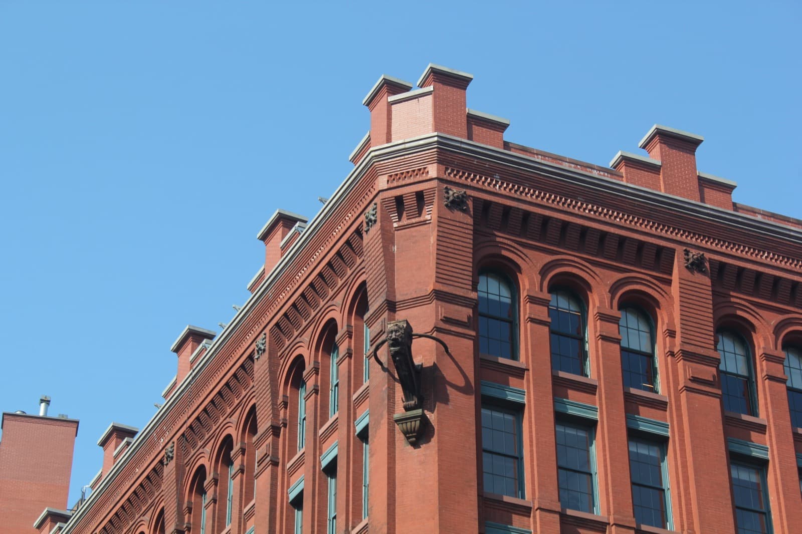 A red-brick building with tall round-arched windows against blue sky