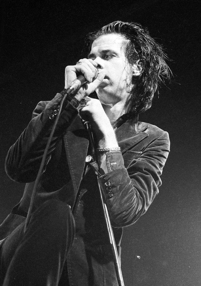 Nick Cave singing into a hand-held microphone, black-and-white